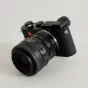 Urth Lens Mount Adapter, savienojot Nikon F (G‑Type) objektīvu ar Leica L kameru, redzams no trīs ceturtdaļu leņķa ar Nikon AF‑S NIKKOR objektīvu un manuālo fokusa pārslēgu.