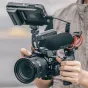 Falcam F22 F38 F50 horizontal to vertical quick release circular half cage mounted on a Sony E-mount camera, with top monitor, Rode microphone, and handgrip, held by a photographer.