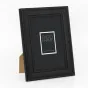 Zep Photo Frame DT434B Spoleto Black 30x40 cm, черная пластиковая рамка с классическим квадратным профилем и рельефной отделкой, представлена в вертикальном положении на небольшой картонной подставке, вид спереди с белой этикетк