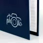 Zep Photo Frame XF468B альбом с синим покрытием и белым логотипом камеры 'photo', частично открытый, чтобы показать белые внутренние страницы