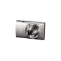 Серебряная компактная камера Canon IXUS 285 HS с выдвинутой 12-кратной оптической линзой, встроенной вспышкой и кнопками управления, изображена спереди на чистом белом фоне.