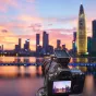 Godox X3Pro C 2.4G touchscreen TTL transmitter mounted on Canon camera with cityscape backdrop at sunset
