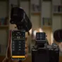 Godox X3Pro C 2.4G touchscreen TTL transmitter connected to Canon camera with cable displaying lighting group settings on screen and included charging case with USB-C cable and storage pouch