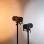 Две батарейные вспышки Godox Witstro AD400 Pro II, установленные на стойках, демонстрируют компактный дизайн и функции беспроводной синхронизации на градиентном фоне от теплого оранжевого до холодного белого.