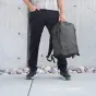 Wandrd PRVKE 31 Zip Black backpack with top zipper access and rugged design, held by a person outdoors near a concrete wall.