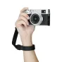 JJC WS 1 Deluxe ātrās atbrīvošanas rīkstas josta melnā krāsā ar pievienotu kompakto fotoaparātu, demonstrējot drošu stiprinājumu un regulējamu komforta fit.
