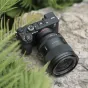 Viltrox AF 35mm F1.2 LAB objektīvs Sony E-mount kamerai ar ultraplatu atvērturi un augstas kvalitātes uzbūvi, novietots ārā uz teksturētas akmens virsmas ar zaļumiem fonā.