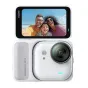 Insta360 Go Ultra akcijas kamera baltā krāsā ar aktīvu displeju, kurā redzams pludmales pašaizņēmuma attēls, kompaktā dizainā ar magnētisko fiksācijas iekārtu un objektīva redzamā puse