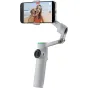 Insta360 Flow 2 Pro AI Tracker Bundle in use with smartphone recording a selfie of a woman and dog at the beach, showcasing magnetic clamp and 3-axis stabilization