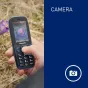 Компактный телефон Panasonic KX-TF400EXC синего цвета с камерой, отображающий фото цветка на экране 2.4 дюйма, натурный снимок на улице