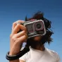 Insta360 Ace Pro 2 with Tilta Xplorer Grip Kit in gray, ergonomic grip for street photography and urban travel, handheld use against a clear blue sky