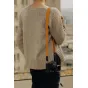 Peak Design Form Leather camera strap in amber with low-profile Anchor Link connectors, worn over a knitted sweater for a sleek, minimalist look