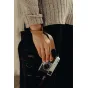 Peak Design amber leather cuff wrist strap with black metal anchor, secured on wrist for camera support