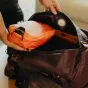 Peak Design Packing Cube Small in ibis orange inside an open Peak Design backpack, showcasing its dual compartments and compression design