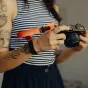 Нарукавный ремень Peak Design Cuff в использовании с DSLR-камерой, демонстрирующий регулируемую магнитную застежку и надежную фиксацию для защиты от падений