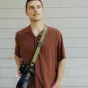 Ремень для камеры Peak Design Slide Lite Kelp с системой Anchor Link, закреплённый на DSLR-камере в режиме плечевого ремня, с текстурированным ремнем для надежного захвата