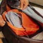 Peak Design Packing Cube Medium oranžs un melns ar atskalojamo UltraZip, atvērts, lai parādītu divus nodalījumus tīriem un netīriem apģērbiem.