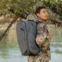 Peak Design Travel Backpack 45L in ocean grey, rugged and expandable with multiple access points, worn by a traveler outdoors near water and greenery.