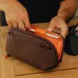 Peak Design Tech Pouch Small atvērts ar stilusu elastīgajā cilpā, kompakts tehnoloģiju organizators uz koka virsmas