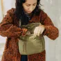 Peak Design Field Pouch V2 kelp green – compact expandable camera bag with adjustable strap, open roll-top closure showing internal stretch pockets and weatherproof nylon shell