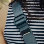 Close-up of the Peak Design Slide Lite camera strap in Ocean color, featuring the Anchor Link connector and textured nylon webbing with smooth and grippy sides, along with visible hardware like quick-adjusters and silicone grip.