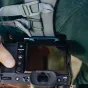 Peak Design Capture Clip V3 okeāna krāsā nostiprināta pie fotoaparāta remena ar ātri atbrīvošanas pogu, lai ātri mainītu objektīvus un droši pārvadātu
