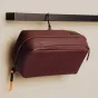 Burgundy Peak Design Wash Pouch with weatherproof UltraZip, built-in aluminum hook, and durable silicone-coated mesh pockets for organized travel essentials.