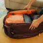 Peak Design Travel Duffelpack 65L open view showcasing spacious interior with orange lining, expandable 65L capacity, and sturdy zippers.