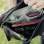 Peak Design Outdoor Sling 4L black cross-body bag featuring a camera lens, sunglasses, and organized compartments for adventure essentials.