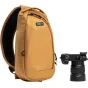 Think Tank TurnStyle 5L Golden Hour siksnas soma ar melnu sietu aizmugures paneli, divām rāvējslēdzēju kabatām, drošu priekšējo kabatu un kameru klipšu sliedi, blakus ir Sony Alpha DSLR ar 24-70mm objektīvu.