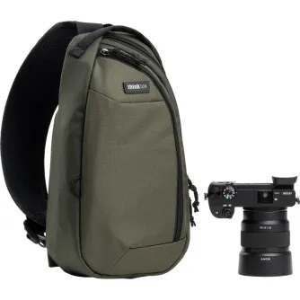 Zaļā Think Tank TurnStyle 5L sling bag ar Sony DSLR kameru un lielo objektīvu, ar mīkstu planšetdatora kabatu un regulējamu plecu siksnu.