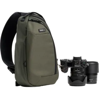 Zaļa Think Tank TurnStyle 8L šulpiniekā ar kameru montēšanas rāli, Nikon DSLR un objektīvu, kas piestiprināts pie plecu siksnas.