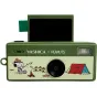 YASHICA Funtastic atslēgu piekariņa kamera ar zaļu korpusu, melnu objektīvu, plīša ekrānu un zibspuldzi, ar Snoopy kempinga ainu priekšpusē.