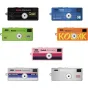 Kodak Charmera Millennium atslēgu piekariņu digitālās kameras, izvietotas režģī, ar unikālām krāsām un dizainiem: melna ar zelta akcentiem, zila ar daudzkrāsainiem punktiem, zaļa ar svītrām, oranža ar pikselētu tekstu, rozā ar g
