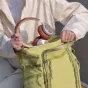 Zaļš PGYTECH OneGo Roamer Tote Backpack 18L ar kameru somas ieliktni un sarkaniem austiņām, demonstrējot divas nēsāšanas iespējas un viedās piekļuves funkcijas.