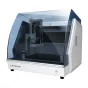 CNC рутер Carvera с прозрачным защитным кожухом, демонстрирующим внутренние компоненты, такие как шпиндель, лазерный модуль и систему удаления пыли, установленный на белой поверхности с кнопками управления и функциями безопаснос