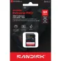 SanDisk Extreme PRO 64GB SDXC UHS-I pamuņakarte tirdzniecības iepakojumā ar kameru lēcu fonā