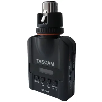 Kompakts Tascam DR-10X mikrofona pievienojams audio rekorders ar XLR mikrofonu, priekšējais skats ar OLED ekrānu, vadības pogām un slīdošo ierakstīšanas slēdzi, melns korpuss, ideāls laukā ierakstīšanai.