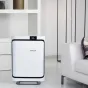 BONECO P500 Air Purifier with sleek white front panel and black trim, displayed in a modern living room beside a white sofa, featuring a digital display and HEPA filter for pollen, dust mite and odor removal