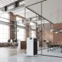 White BONECO P710 air purifier for large areas in a modern office with glass partitions and exposed brick walls