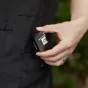 A hand holds a black Godox XR TTL Trigger Receiver with a silver front panel, connected to a camera via a cable. The 0.96-inch TFT screen displays settings against a blurred green background.