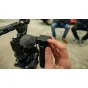 Hand holding a GoPro Wireless Mic transmitter from the Complete Kit, showing green LED level indicators and attached to a camera rig with a furry windscreen, highlighting the clippable, magnetic design of the wireless lavalier m