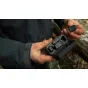 GoPro Wireless Mic Complete Kit open charging case displaying two compact transmitters and a USB‑C receiver, with a hand holding a magnetic transmitter featuring the GoPro logo, showcasing the portable wireless lavalier micropho