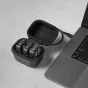 Rode Wireless GO Charge Case+ open, holding three Wireless GO transmitters with green charging LEDs, connected via USB‑C cable to a laptop on a speckled surface.