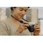 Черный Peak Design Form Rope Neck камера-ремень обхватывает женщину, держащую Fujifilm X‑E5 беззеркальную камеру, подчеркивая минималистичный нейлоновый шнур и низкопрофильные быстросъемные крепления.