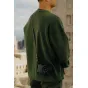 Peak Design Form Leather Long черный ремень для камеры, надетый на человека в зеленом свитере, с черной камерой, на фоне городской панорамы с крыши.