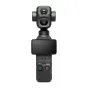 DJI Osmo Pocket 4P Vlog Combo ar divām kamerām, ekrānu, vadības pogām un sarkano ieraksta pogu, uz statīva ar pārvadāšanas somu un aksesuāriem fona.