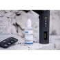 Newell 60 ml smoke liquid bottle for fog machines, displayed with a remote control and cordless fog machine on a stone surface