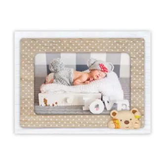 Wooden baby photo frame Zep NB9564 Yoghi 10x15 cm, featuring a sleeping newborn in a knitted outfit and gray hat with a red bow, accompanied by "LOVE" letters and a plush teddy bear, set against a beige polka-dot background.