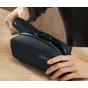 Person removes the DJI Osmo Pocket 4P camera from its black OSMO branded carrying bag on a light wooden surface, highlighting the compact protective storage solution.